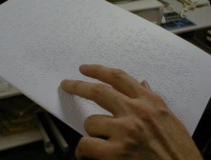 Close up of a hand scanning over Braille