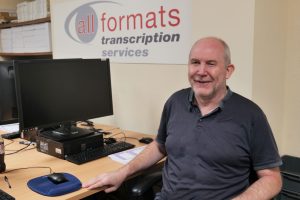 Image of Paul sat at his desk with the All Formats logo in the background