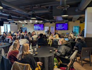 Image of the crowd and panellists in a room talking